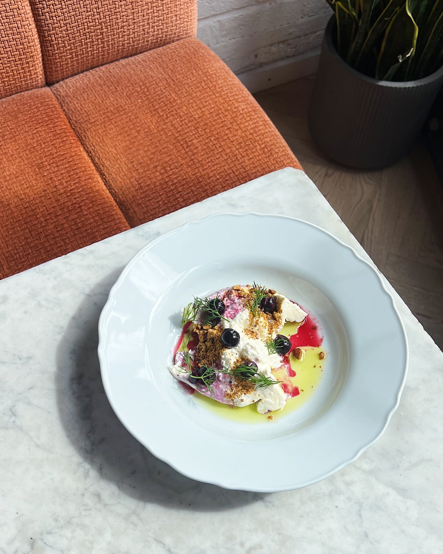 Plated dish on a marble surface with an orange chair and plant in the background