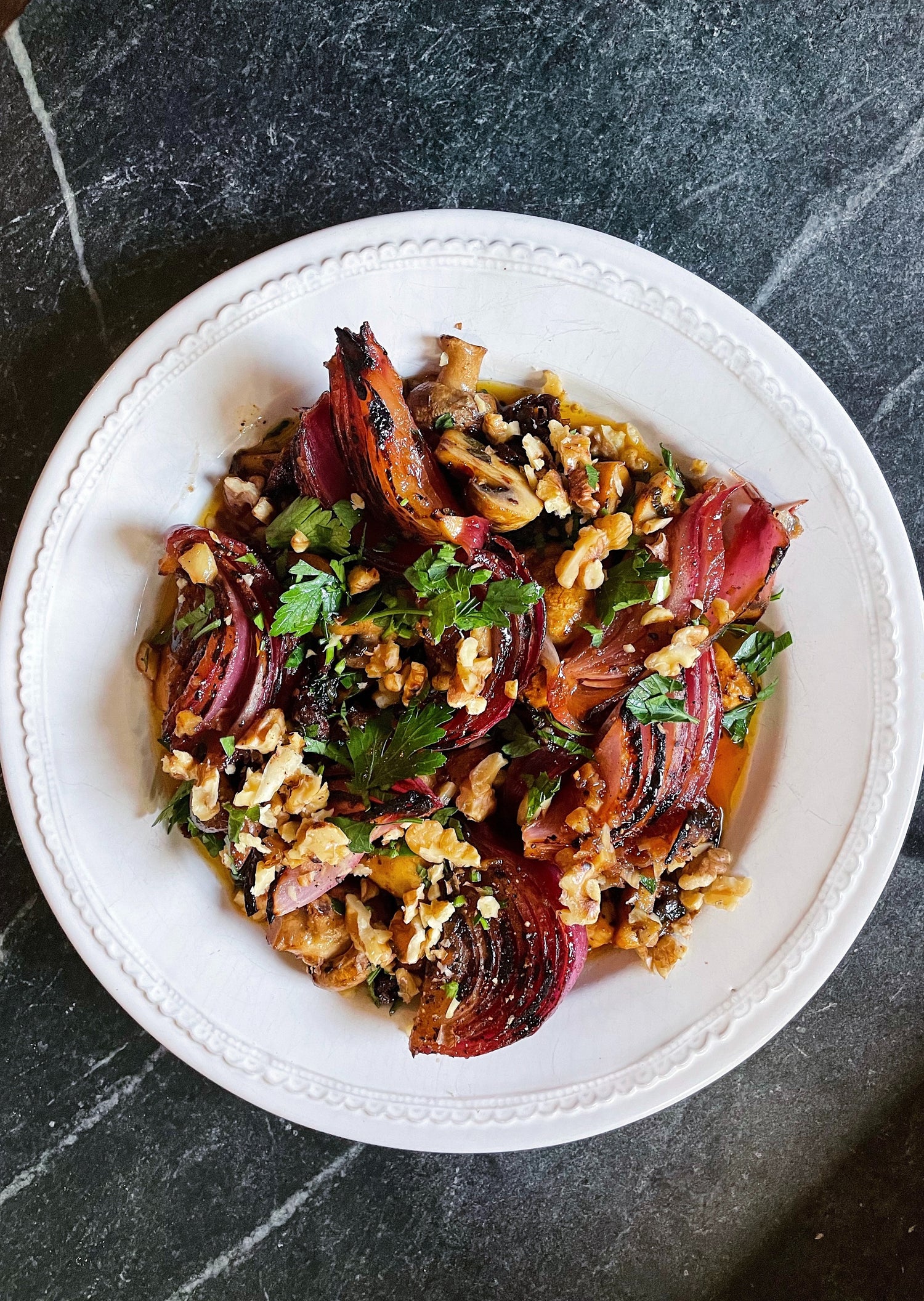 Plated dish of roasted vegetables with herbs on a dark surface