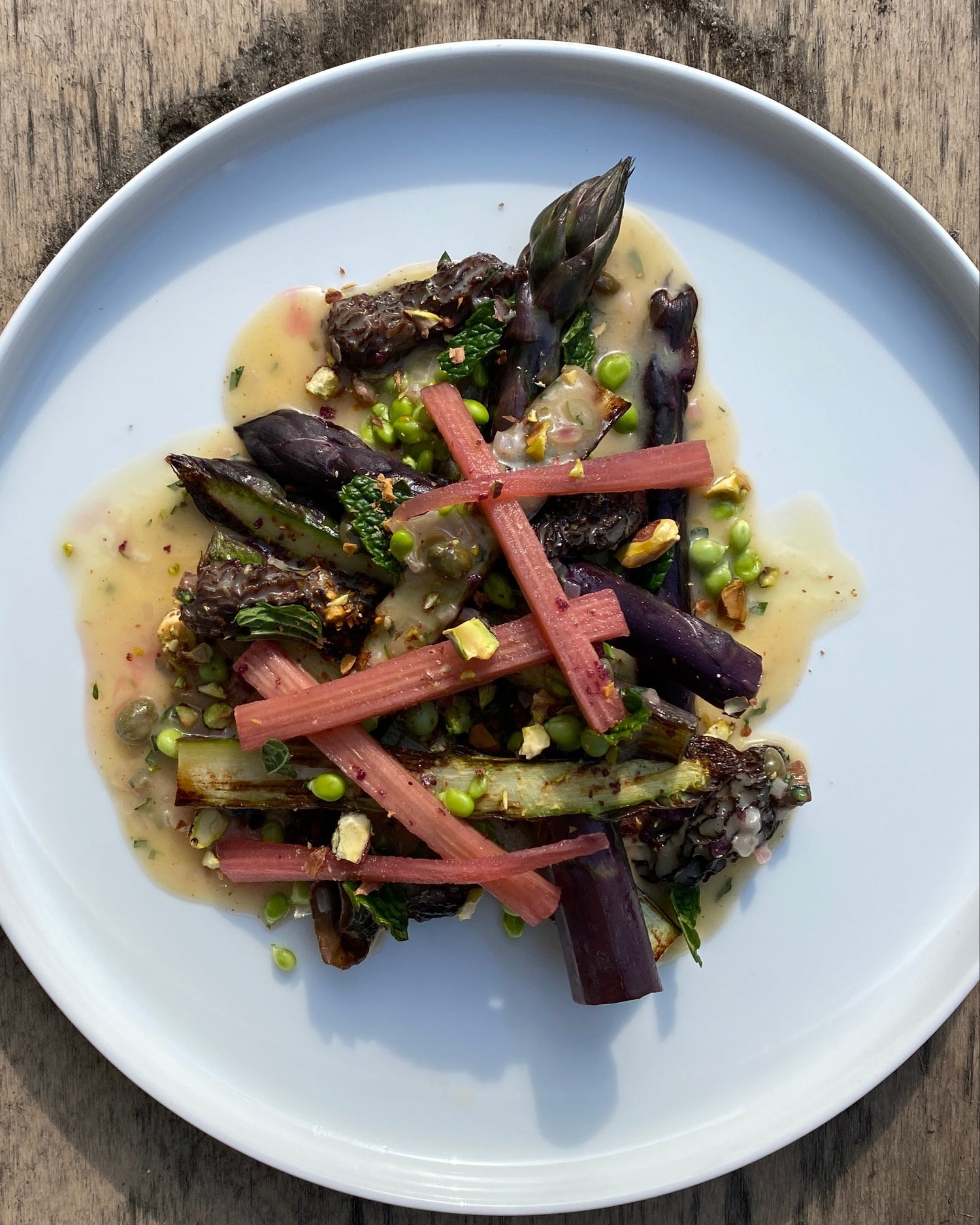 Plated dish with asparagus and other vegetables on a wooden surface
