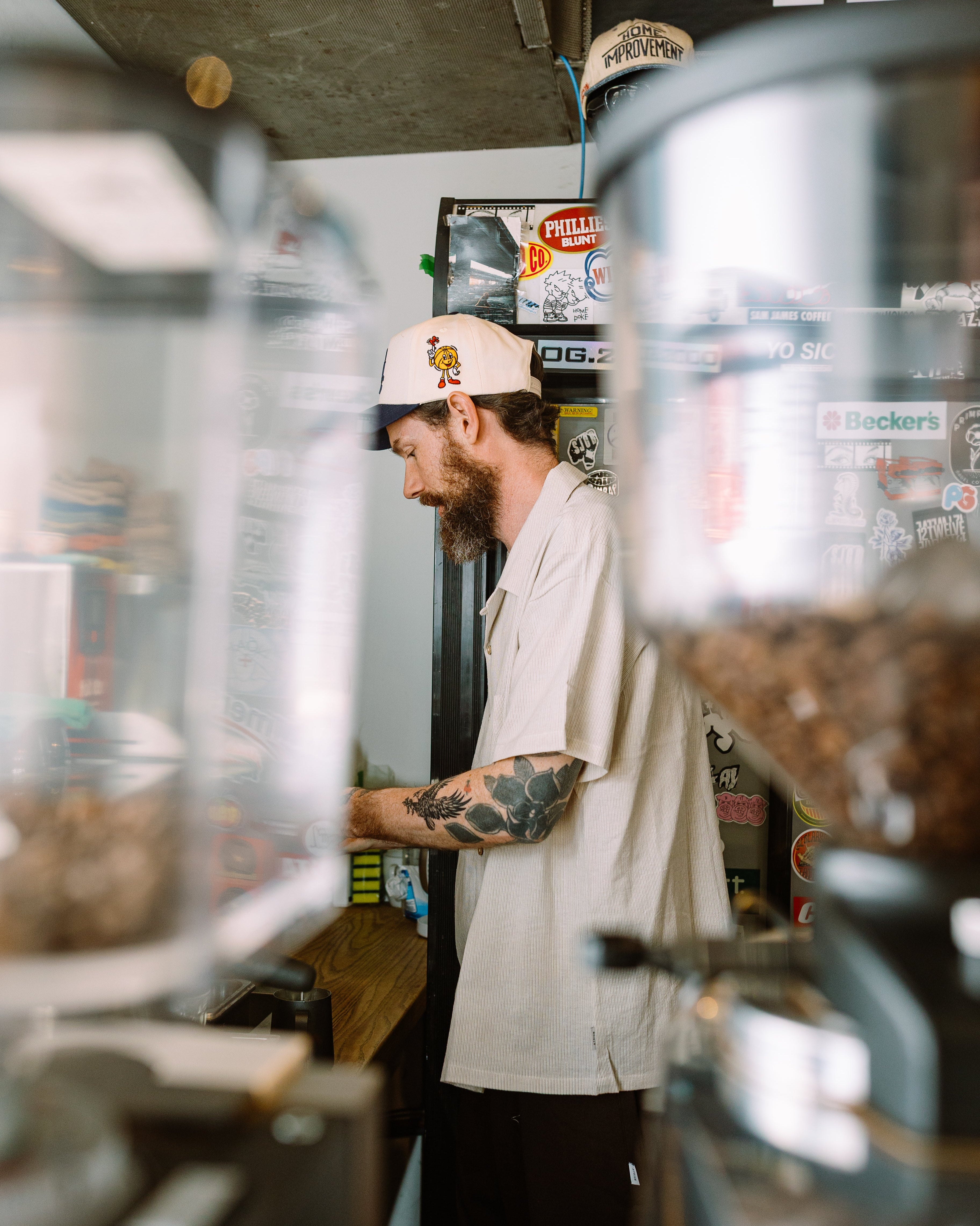 Man with tattoos working behind a counter in a casual setting